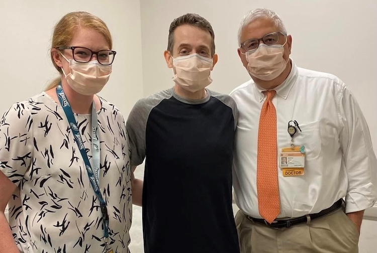 Three people standing together for a photo in facemasks.